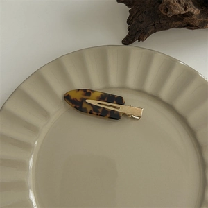Close-up of a large leopard print hair claw clip on a ceramic plate with wooden decor