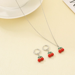 Detailed close-up of a silver cherry necklace and earrings set with red enamel accents