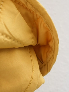 Detailed macro view of yellow plaid jacket fabric texture and reinforced stitching work