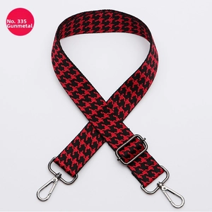 Detail of red and black houndstooth bag strap with adjustable gunmetal metal hardware