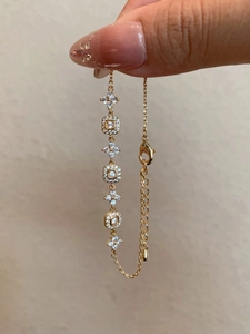Close-up of 18K gold plated bracelet with cubic zirconia flower and square links