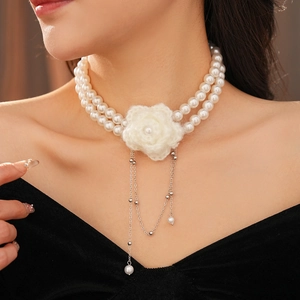 Close-up of double-layer pearl necklace with white knitted flower and silver metal tassels
