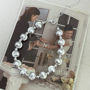 Detail of silver bead bracelet with brushed texture and lobster clasp on magazine
