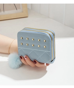 Détail du porte-monnaie bleu clair à rivets avec double zip et charm boule en peluche