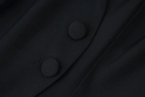Detail of fabric texture and black fabric-covered buttons on a stand collar long sleeve top