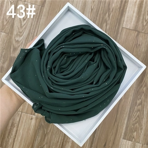 Détail d'un foulard en mousseline vert foncé avec paillettes argentées sur un plateau