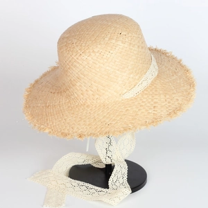 Close-up of raffia sun hat featuring frayed edges and elegant white lace ribbon tie