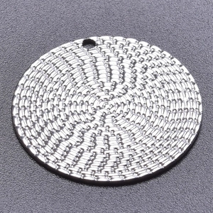 Macro shot of silver stainless steel round pendant with detailed woven texture and bail