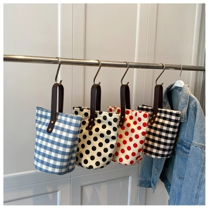 Close-up of canvas bucket bags with polka dots and plaid patterns with leather handles