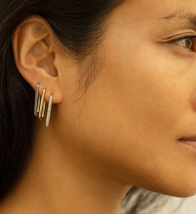 Close-up of three U-shaped 925 silver earrings in gold, silver, and pavé diamond styles