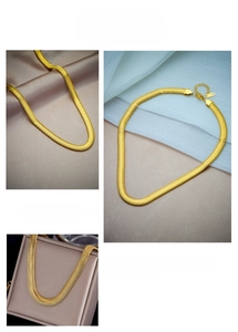 Detail of flat golden snake bone chain with high-gloss texture and lobster clasp closure