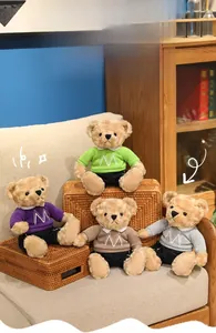 Detailed view of four colorful teddy bears in M-embroidered t-shirts on a sofa