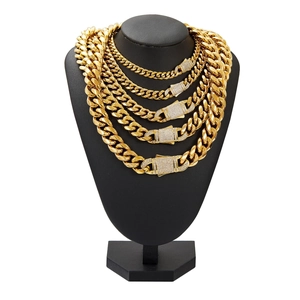 Five gold Cuban link chains with micro-pave zircon clasps on a black jewelry stand
