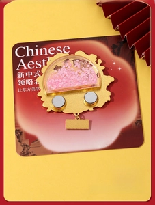 Detail view of pink floral metal magnetic pin with golden base on yellow background