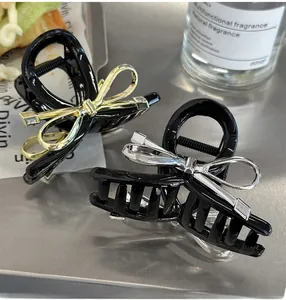 Detail of black bow hair claw clips with gold and silver accents on a modern surface