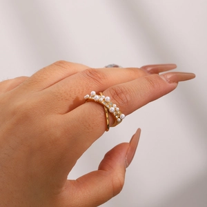 Bague en acier titane doré avec perles et strass portée à l'index pour femme