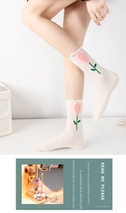 Close-up of white cotton mid-calf socks featuring pink tulip flower embroidery and wavy edges