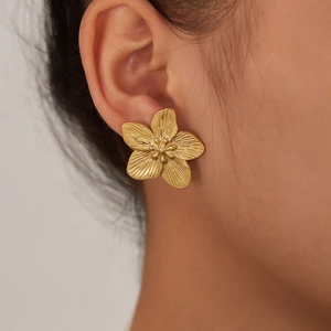 Close-up of vintage gold floral earring with textured petals on a female model