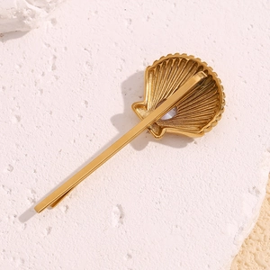 Detail of 18K gold plated stainless steel scallop hair clip with shell texture and pearl