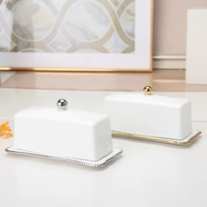 Detailed view of white ceramic butter dishes with elegant gold and silver beaded edges