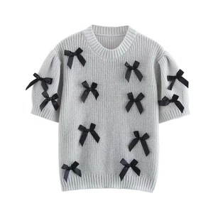Gros plan détaillé du pull en tricot gris à manches courtes avec nœuds en satin noir