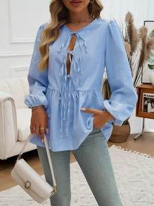 Detail of blue striped blouse featuring tie-front neck and peplum hem design