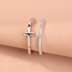 Close-up of a silver cross ring and micro-paved eternity band set on a display cone