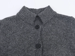 Detail of grey knitted cardigan with gold thread, high neck, and black buttons