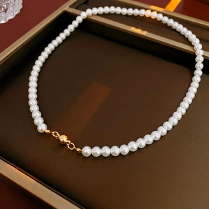 Close-up of elegant white pearl necklace with a minimalist gold magnetic clasp design