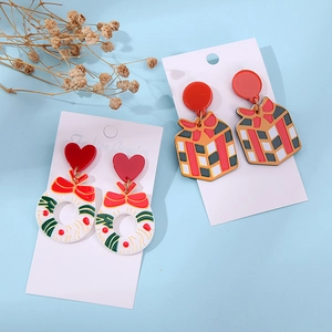 Detail of Christmas wreath and gift box acrylic earrings on light blue background
