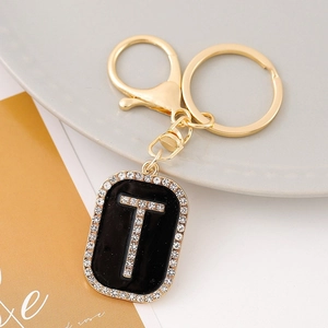 Macro shot of letter T rhinestone keychain with black enamel finish and golden hardware
