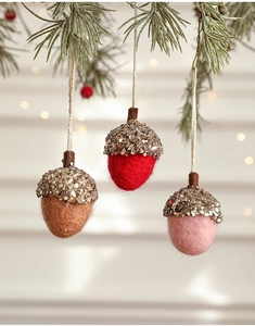 Three felt pinecone ornaments with gold glitter tops hanging on frosted pine branches