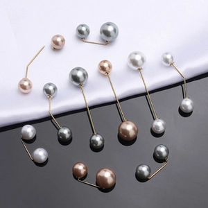 Detailed view of elegant faux pearl pins in gold finish on silk and mirror background