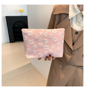 Detailed view of pink pouch featuring 3D white floral embossed texture and soft fabric