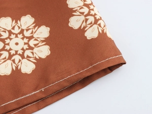 Detailed view of coconut tree print on brown fabric with white stitching detail