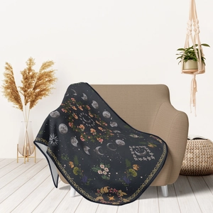 Celestial moon phase flannel throw blanket draped over a modern beige sofa in cozy room