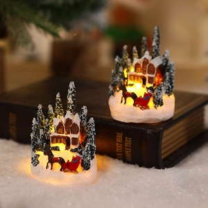 Detail of glowing Christmas resin houses with snow and sled figures in a warm micro landscape
