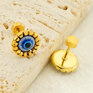 Retro titanium steel gold evil eye stud earrings on a textured stone and linen background