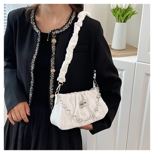 Close-up of white pleated shoulder bag with floral silver chain and textured fabric
