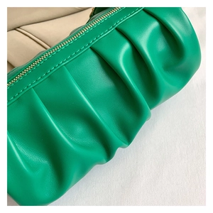 Close-up of green pleated handbag leather texture and premium gold zipper detail