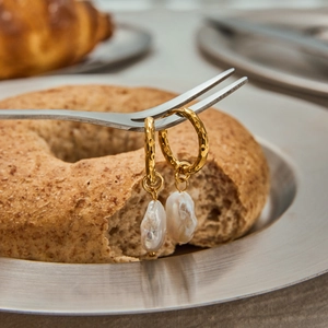 Baroque pearl drop earrings with golden hammered metal texture on creative table setting