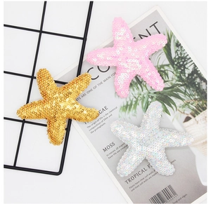 Detailed view of colorful sequined starfish hair clips in pink, gold, and white shades