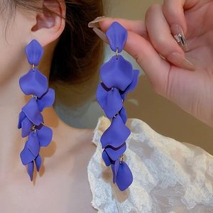 Macro view of purple matte petal tassel earrings with gold connectors on model