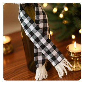 Close-up of a festive black and white plaid mini scarf decoration with fringe on a wine bottle