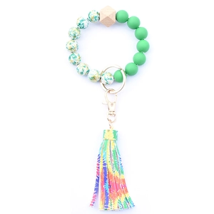 Detail of beaded key ring with green beads, wooden hex bead and colorful tie-dye tassel