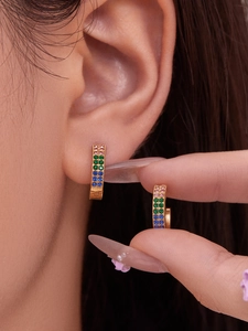 Close-up of gold-plated hoop earrings with pink emerald and blue pavé crystal settings