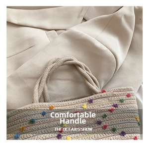 Macro detail of hand-woven bucket bag with colorful pom-pom decor and braided handle