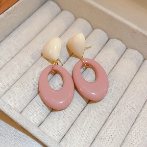 Close-up of contrast color resin heart earrings with oval charms in a jewelry box