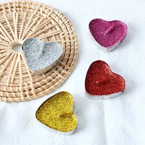 Glittering heart-shaped candles in gold, silver, red, and purple for romantic decor