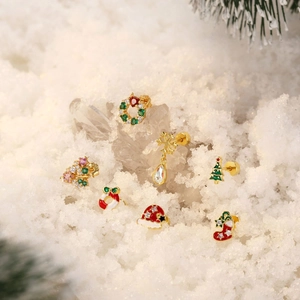 Set of 7 gold Christmas studs with wreath, tree, and snowflake on artificial snow
